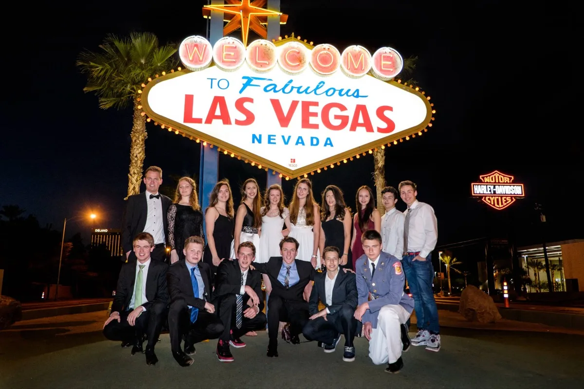 Festlich gekleidete Austauschschülerinnen und Austauschschüler einer CYE-Gruppe stehen abends vor dem Leuchtschild Welcome to Fabulous Las Vegas.