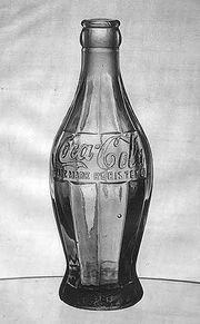 Eine bauchige Glasflasche mit eingeprägtem Coca-Cola-Schriftzug
