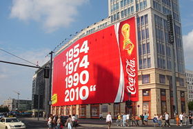 Ein großflächiges Plakat an einem Berliner Haus mit den Jahreszahlen 1954, 1974, 1990 und 2010 und einem Fußballpokal