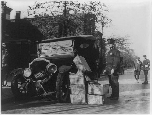 Ein Polizist steht neben einem Wagen und gestapelten Kisten