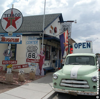 Ein Ladengebäude mit Texaco-Schild und alten Route-66-Schildern, davor ein Pick-up